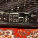 Detailní pohled na zadní panel černého kytarového komba. Na panelu jsou nápisy BUGERA, TRIREC INFINIUM, ZHONGSHAN EUROTEC ELECTRONICS LTD MADE IN CHI…