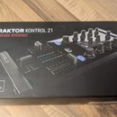 Fotografie znázorňuje černou kartonovou krabici s produktem Traktor Kontrol Z1. Na povrchu je nápis TRAKTOR KONTROL Z1 DJ MIXING INTERFACE, logo NI a…