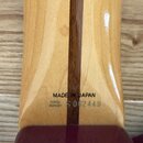 Detail zadní strany krku kytary zCvlákněného světlého dřeva s tmavým středovým pruhem. Na dřevě je černý nápis MADE IN JAPAN a vedle něj sériové čísl…