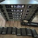 Stoh čtyř stříbrných rackových jednotek s digitálními displeji a ovládacími prvky, na nichž je nápis beyerdynamic. Před jednotkami leží dva černé bez…