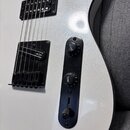Detail bílé elektrické kytary s metalickým povrchem. Na snímačích a mostku je vidět nápis SR. Kytara má černý ovládací panel se dvěma potenciometry s…