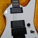 Bílá elektrická kytara s černým hmatníkem a černými komponenty, umístěná v žlutém plišovém pouzdře. Nástroj má dva humbuckery s nápisem EMG a černý m…