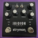 Černý kytarový pedál s nápisy IRIDIUM, amp & ir cab a značkou strymon. Zařízení má čtyři ovládací knoflíky s popisky DRIVE, MIDDLE, TREBLE a LEVEL, d…