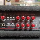 Detailní pohled na ovládací panel basového zesilovače značky CARVINE. Panel je červený s bílými nápisy, včetně modelu RED LINE STEREO BASS AMP a graf…