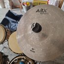 Fotografie zachycuje stříbrný kovový činel typu splash s koncentrickým žebrováním povrchu. V horní části je černý nápis ABX cymbals a v dolní části n…