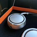 Fotografie zachycuje stříbrná sluchátka v oranžovém obalu s černou vložkou. Na horním okraji mušle je nápis NEUMANN.BERLIN a STUDIO HEADPHONE KH 80.…