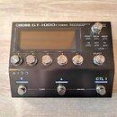Černý kytarový efektový procesor s nápisem BOSS GT-1000CORE GUITAR EFFECTS PROCESSOR. Zařízení má digitální displej, pět ovládacích knoflíků v řadě a…