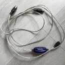 Stříbrný USB MIDI kabel s modrým plastovým převodníkem. Na převodníku je bílý nápis USB MIDI. Kabel má na koncích konektory USB a dva 5pinové DIN kon…