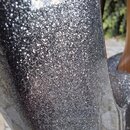 Detailní záběr na povrch hudebního nástroje s tmavě šedou nebo černou barvou. Povrch má výrazný metalický efekt s hustým třpytivýmleskem. Na fotograf…