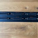 Záběr na zadní panel černého elektronického zařízení s řadou konektorů. Jsou zde tři D-Sub konektory označené nápisy output 17-24, output 9-16 a outp…