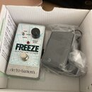 V bílém kartónovém boxu je efekt pedál stříbrné barvy s nápisy FREEZE, SOUND RETAINER a značkou electro-harmonix. Pedál má jeden černý ovládací knofl…