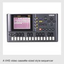 Snímek zachycuje produktovou fotografii přenosného sekvenceru v černé barvě. Na zařízení je vidět nápis QY22 MUSIC SEQUENCER a logo YAMAHA. Přístroj…