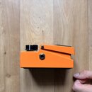 Oranžový kytarový pedál s kovovým tělem a černými ovládacími knoflíky. Na boční straně je umístěn jeden vstupní/výstupní jack konektor. Spodní strana…