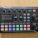 Černý kompaktní zvukový mixér s řadou ovládacích prvků. Na horní části jsou čtyři otočné knoflíky s popisky TREBLE, MID, BASS a RECORD, dva posuvníky…