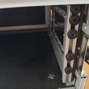 Detail vnitřku transportního kufru s černým dnem a hliníkovými hranami. Na pravé straně je vidět kovová lišta připevněná pěti černými šrouby s křížov…