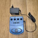 Modrý kytarový procesor V-TONE GUITAR GDI 21 GUITAR AMP MODELER - DRIVER - DI. Zařízení má čtyři ovládací knoflíky s popisky DRIVE, TREBLE, BASS a LE…