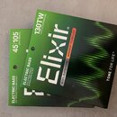 Dvě balení strun pro elektrickou basovou kytaru značky Elixir. Na horním balení je nápis NICKEL PLATED STEEL, NANOWEB TECHNOLOGY a 130TW LIGHT B TAPE…