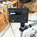 Černý elektronický bicí modul s displejem, na kterém je text DRUM KIT 29 Nebula. Na horní části jsou nápisy Roland a V-Drums. V dolní pravé části je…