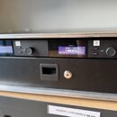 Detailní pohled na přední panel černého rackového zařízení. Na displeji je zobrazen text „channel 2“, „0.81 Oct19“ a frekvence „498.875 MHz“. Na pane…