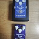 Dvě efektové pedály Deep Blue Delay značky MAD PROFESSOR, BJF DESIGN. Horní pedál je v černém kovovém boxu s modrým ovládacím panelem, spodní pedál m…