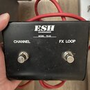Černý efektový pedál s dvěma stáními. Na povrchu jsou nápisy FX LOOP, CHANNEL a MODEL FS-02. Ve spodní části je bílé logo ESH a nápis AMPLIFICATION.…