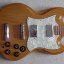 Elektrická kytara s dřevěným povrchem a bílým perleťovým pickguardem. Nástroj má dva snímače typu humbucker, čtyři černé ovládací knofíky a jeden pře…