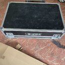 Černý transportní flightcase s hliníkovými hranami a kovovými rohy. Na předním panelu je bílý nápis SIGM a pod ním menší text LIGHT TECHNOLOGY. Povrc…