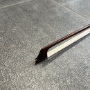 Detailní pohled na špičku smyčce z tmavého dřeva s bílým vlasem. Na samotném hrotu špičky je vidět mírné opotřebení a změna barvy materiálu. Povrch d…