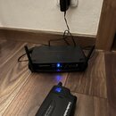 Černý bezdrátový systém značky audio-technica, který se skládá z přijímače a vysílače. Na obou zařízeních je bílý nápis audio-technica a označení SYS…