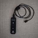 Černý přenosný audio rozhraní s připojeným kabelem a konektorem USB-C. Na zařízení je uveden nápis Groove a logo APOGEE. Přístroj obsahuje dvě kulatá…