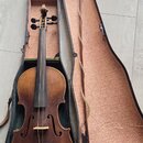Housle s hnědým lakem v černém tvrdém pouzdře s růžovou vnitřní výstlavou. K nástroji patří smyčec umístěný v držáku v víku pouzdra. Povrch nástroje…