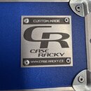 Detailní záběr na kovový štítek připevněný k modrému povrchu transportního case s hliníkovými hranami a rohy. Štítek nese nápisy CUSTOM MADE, logo CR…