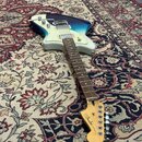 Elektrická kytara s modro-bílým přechodem barvy korpusu a bílým pickguardem. Na hlavě hmatníku je nápis "Fender" a pod ním menší text "MEXICO". Nástr…