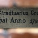 Detailní pohled na papírový štítek uvnitř hudebního nástroje. Na štítku je černým tiskem text „Antonius Stradiuarius Cremonenfs“ a pod ním „Faciebal…