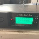 Černý UHF přijímač značky audio-technica. Na předním panelu je zelený displej s hodnotou 656.500 MHz a nápisy ALERT, RF, AF a -TUNER- s označením A a…
