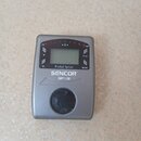 Stříbrný digitální ladicí pedál s plastovým šasi. Na přední straně je displej, kontrolky a nápisy „-50“, „0“, „+50“, „Flat“ a „Mode“. Pod displejem j…