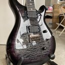 Elektrická kytara s tmavě fialovým průsvitným lakem a výraznou strukturou dřeva na topu. Nástroj má dva humbuckery, chromovaný most s pružinami a jed…