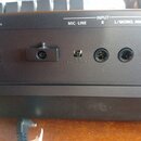 Detail zadní strany černého elektronického zařízení s několika konektory. Jsou zde nápisy DC IN, USE ROLAND PSB-8-7U ADAPTOR ONLY, INPUT, MIC·LINE, R…