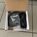 V bílém kartonovém pudejku se nachází černý kytarový zesilovač v plastovém obalu a přiložený černý napájecí kabel. Na přední straně zařízení je bílý…