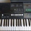 Černý digitální klávesový nástroj značky YAMAHA. Horní panel obsahuje ovládací prvky, displej a nápisy jako SONG, STYLE, MASTER VOLUME a SONG CONTROL…