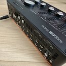 Černý audio rozhraní s oranžovými detaily na spodní hraně. Na horním panelu jsou stříbrné ovladače a nápisy Arturia, AUDIOFUSE STUDIO a ADVANCED AUDI…