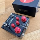 Černý efekt pedál s nápisy NUX a ATLANTIC — delay & reverb —. Zařízení má pět červených oválných ovladačů a jeden stoupací spínač. Vedle pedálu je um…