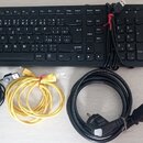 Černá počítačová klávesnice s numerickým blokem, černá optická myš a dva napájecí/datové kabely (jeden žlutý, jeden černý). Na myši je viditelný nápi…