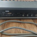 Zadní strana šedého elektronického zařízení značky KORG. Na černém štítku je uveden nápis MODEL, SERIAL NO. 394093, AC V 50/60Hz W a KEIO ELECTRONIC…