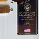 Detail bílého trupu elektrické kytary s nápisem 75th ANNIVERSARY COMMEMORATIVE TELECASTER®. Na černém štítku je logo Fender 75, nápis MADE IN CORONA,…