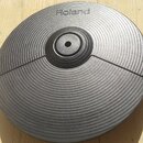 Černý gumový pad elektronického činelu s koncentrickým žebrováním. V horní části je bílý nápis Roland. Povrch vykazuje mírné známky opotřebení a v pr…