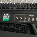 Zadní strana černého míchacího pultu s nápisem Model VX-2442. Na zařízení jsou loga STK Professional Audio a varovné nápisy CAUTION a WARNING, včetně…