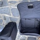 Dvě černé textilní přepravní brašny na hudební nástroje položené na kamenném povrchu. Jedna brašna je zavřená, druhá je otevřená a ukazuje vnitřní pr…