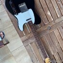 Černá elektrická kytara typu Telecaster s bílým pickguardem a hnědým hmatníkem. Na hlavě kytary je nápis "Spirit" a pod ním "TELECASTER". Povrch čern…