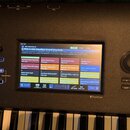 Digitální klavír s černým povrchem a vestavěným barevným displejem TouchView. Na obrazovce je zobrazen seznam zvuků, přičemž vybraný program nese náz…